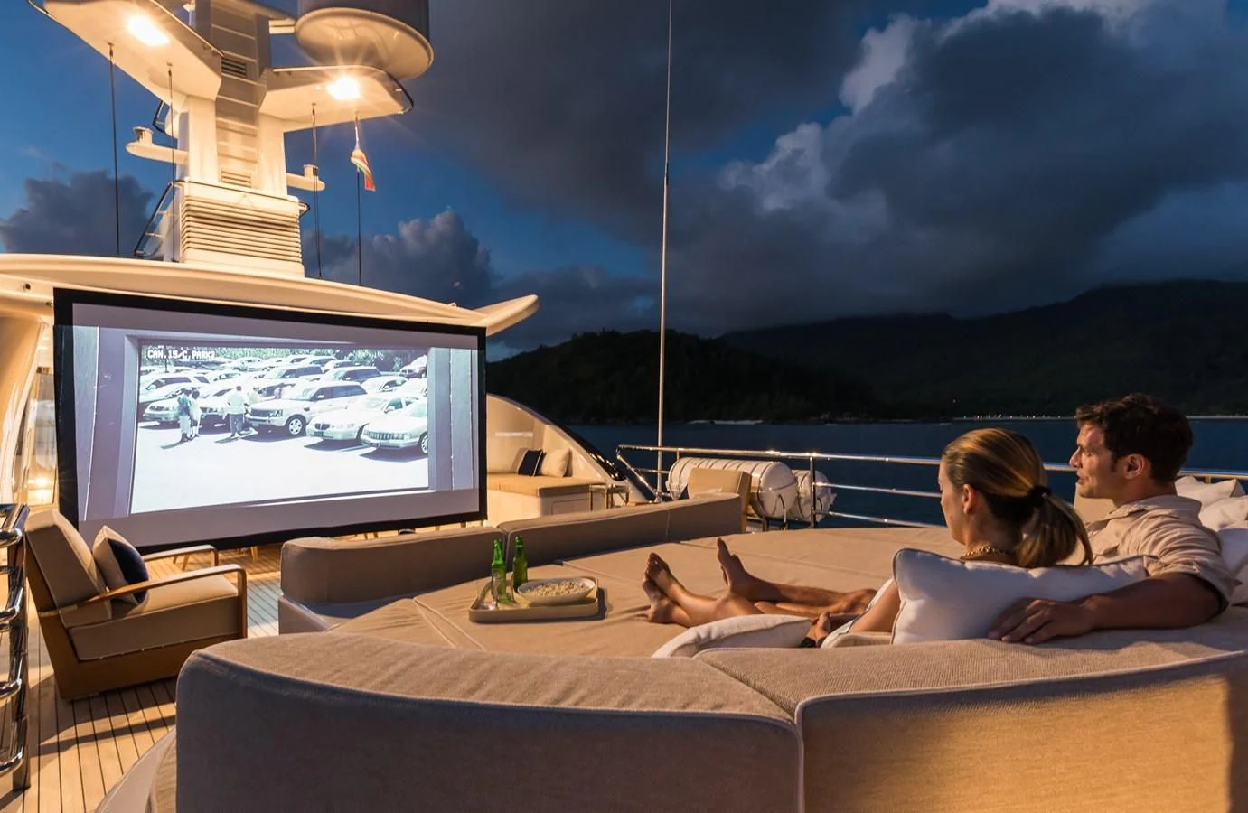 a couple sitting on a couch watching a tv aboard AMIGOS Yacht for Charter