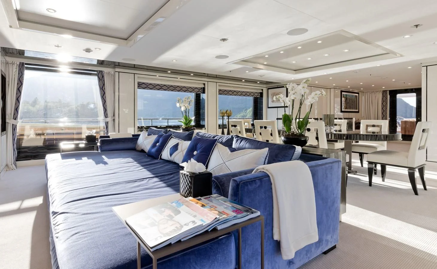 a large living room with a blue couch and a large window aboard AMIGOS Yacht for Charter