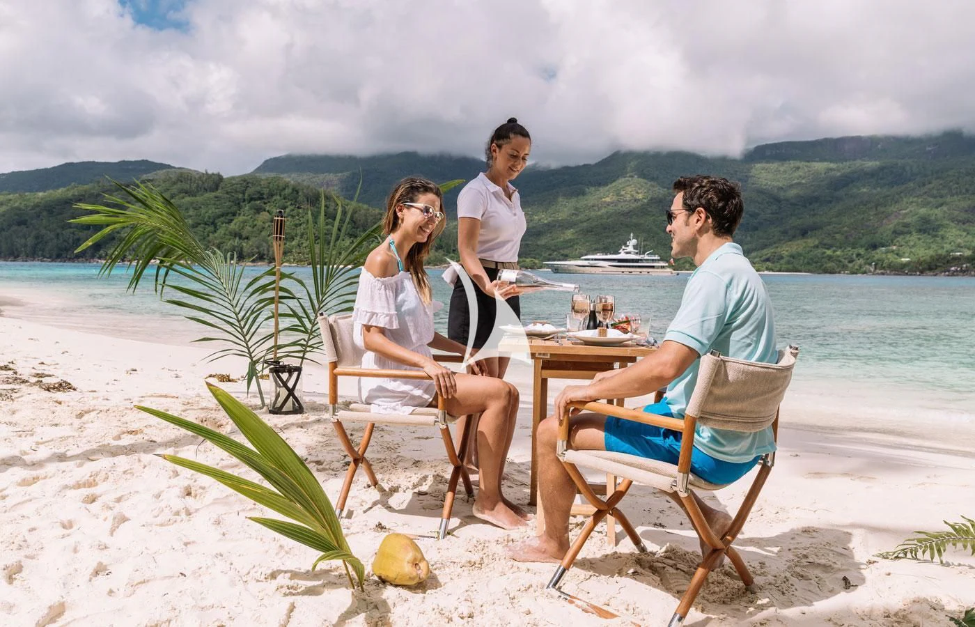 a group of people sitting around a table on a beach aboard AMIGOS Yacht for Charter