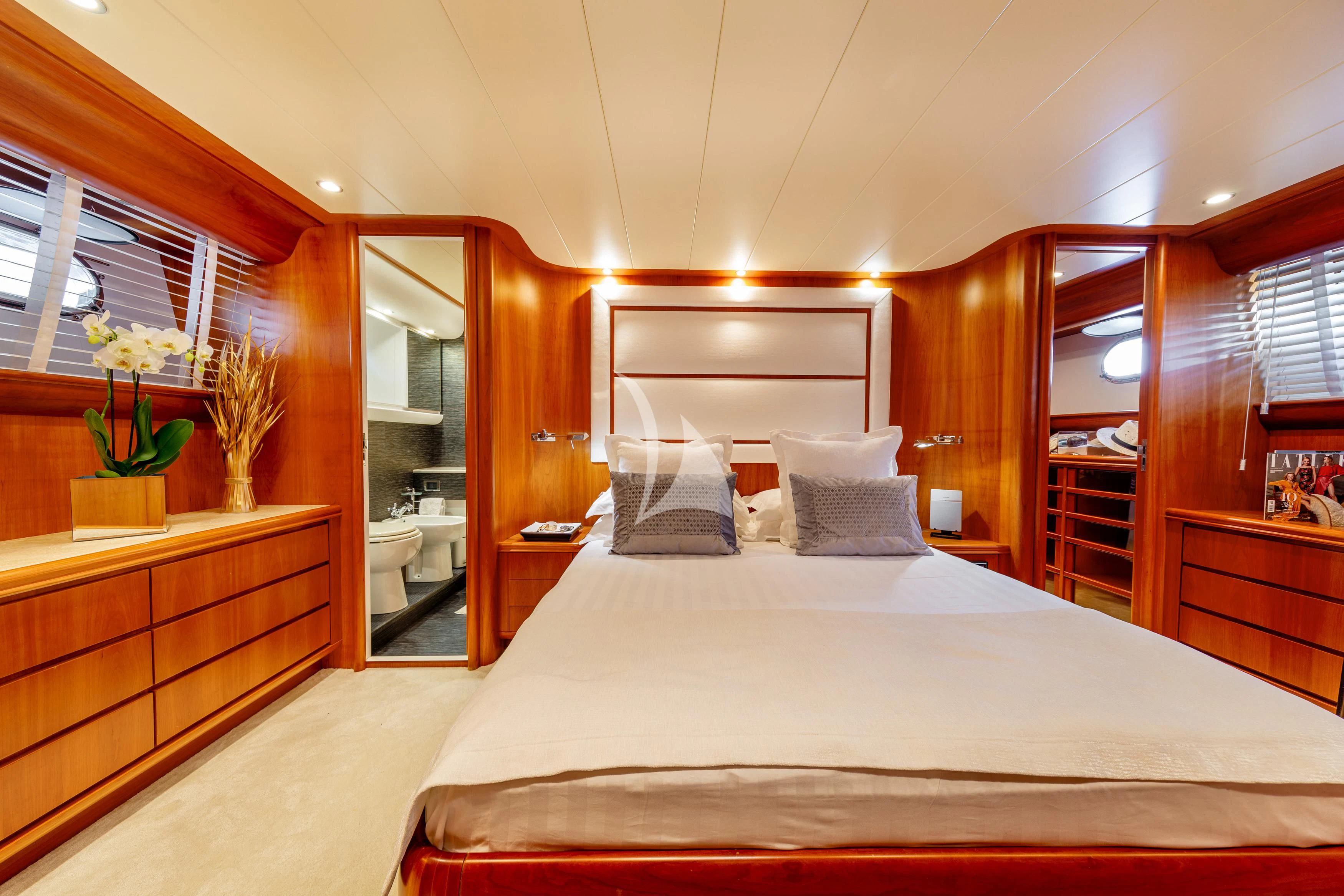 a bed with a white sheet and pillows in a room with wood cabinets aboard WHITEHAVEN Yacht for Sale