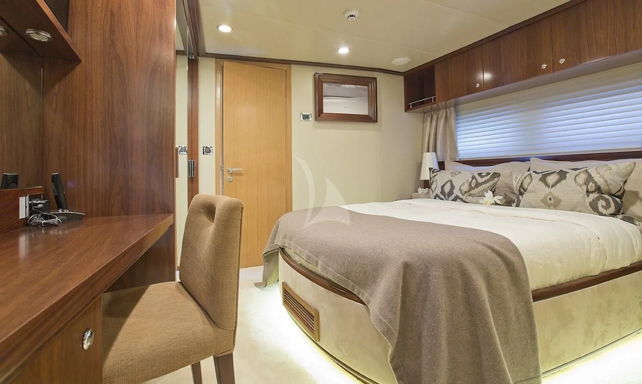 a bedroom with a bed and desk aboard XO OF THE SEAS Yacht for Sale
