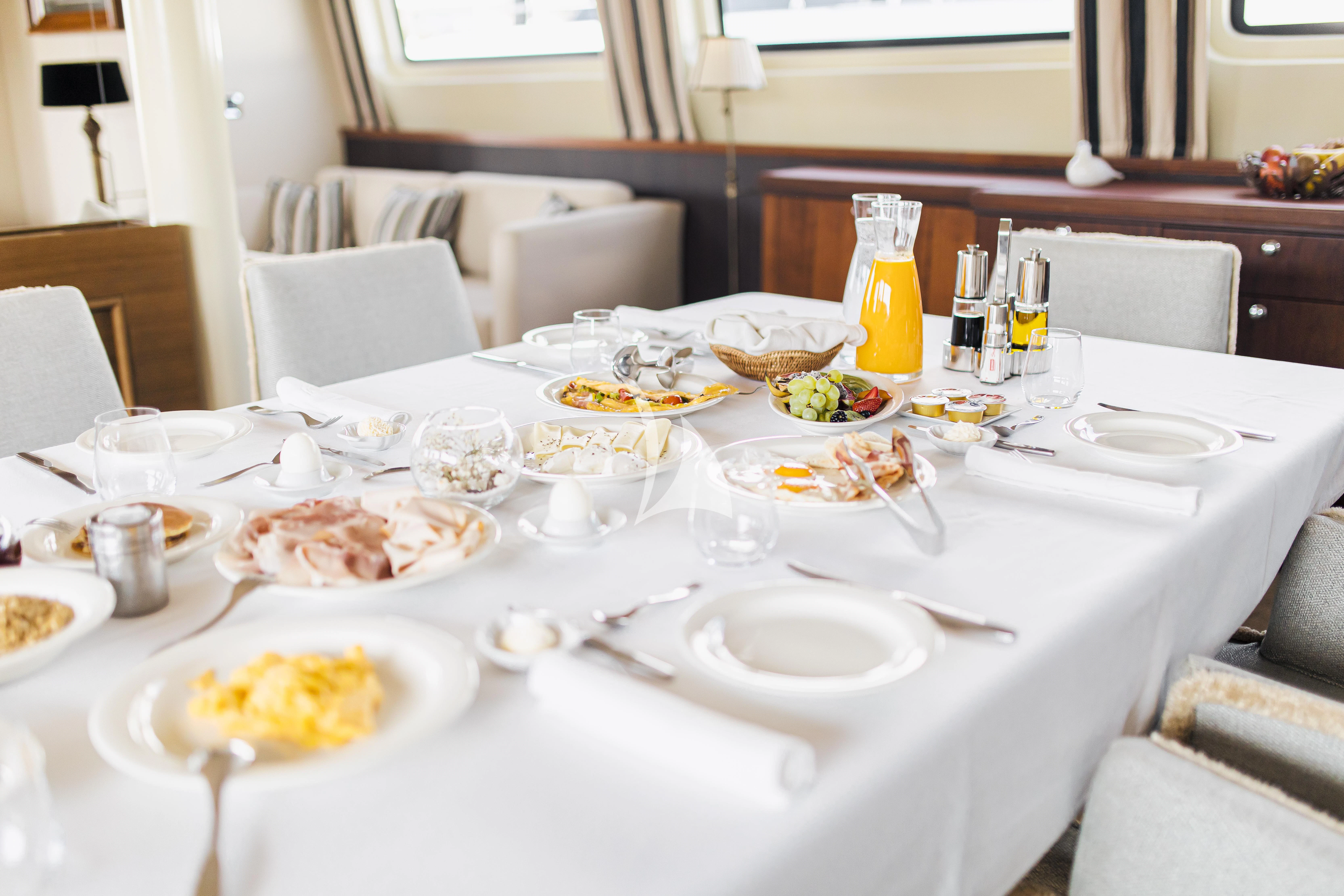 a table with plates and food on it aboard XO OF THE SEAS Yacht for Sale