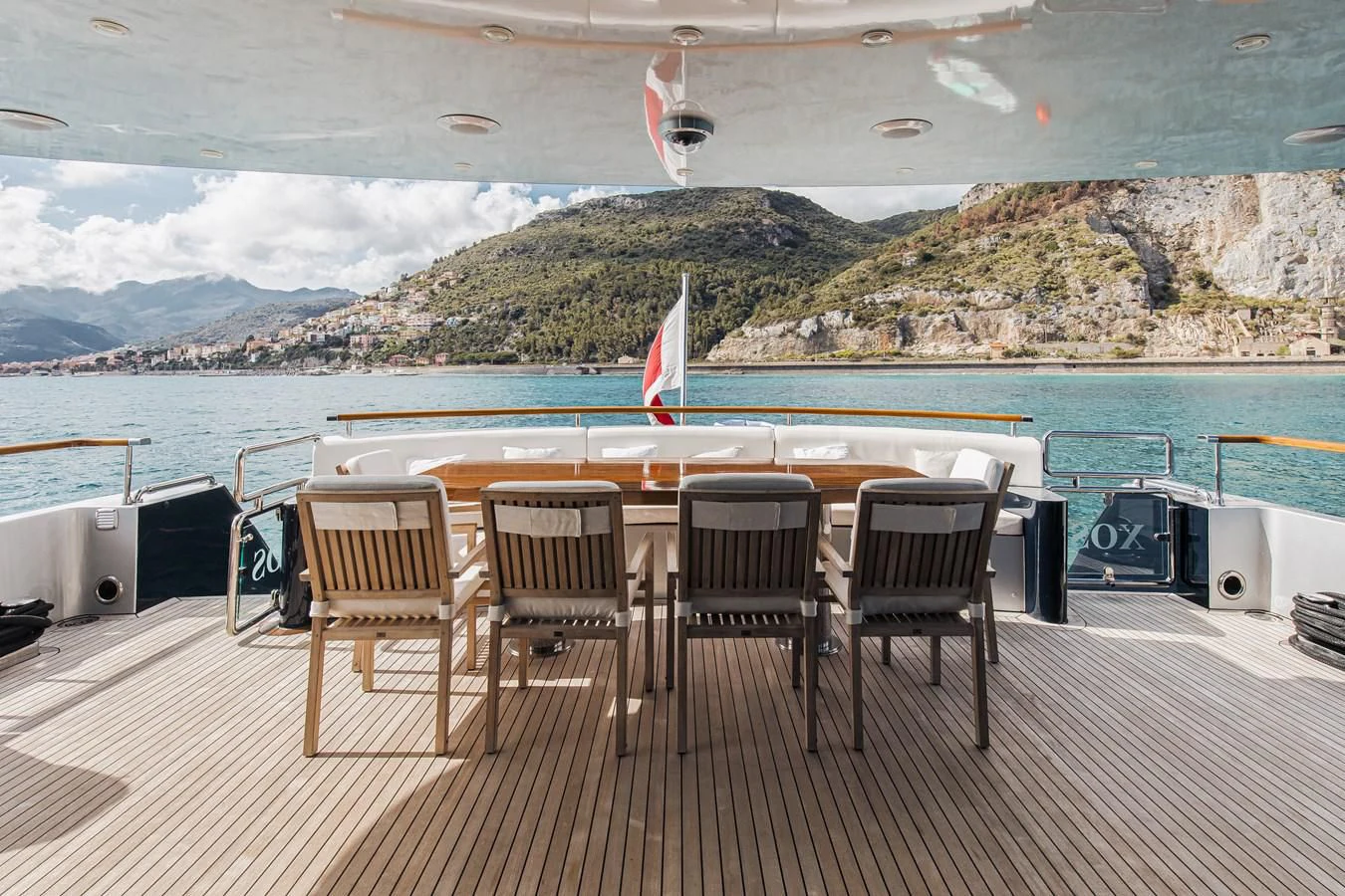 a deck with chairs and a table on it by a body of water aboard XO OF THE SEAS Yacht for Sale