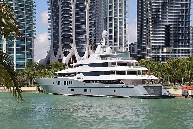 a white boat in a body of water with tall buildings in the background aboard TITAN Yacht for Sale