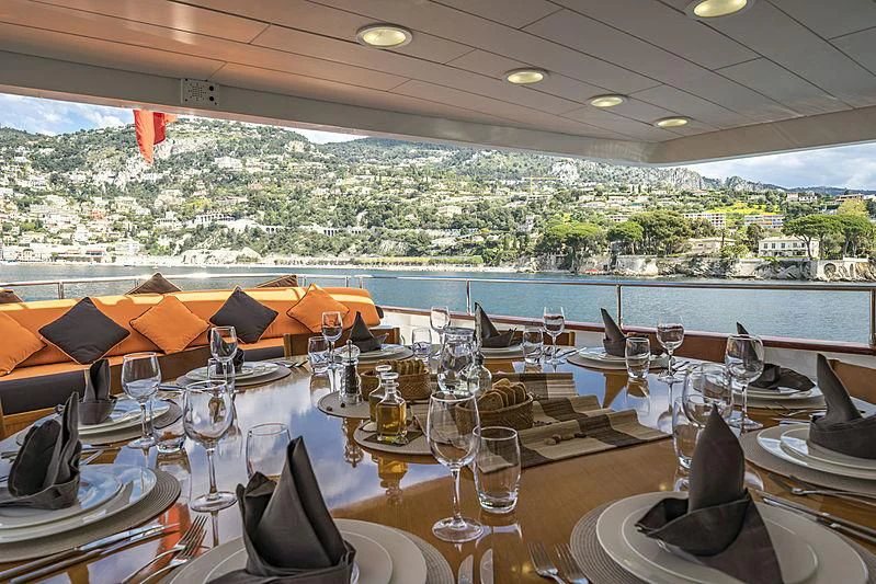 a table with wine glasses and a view of a city aboard FIORENTE Yacht for Sale