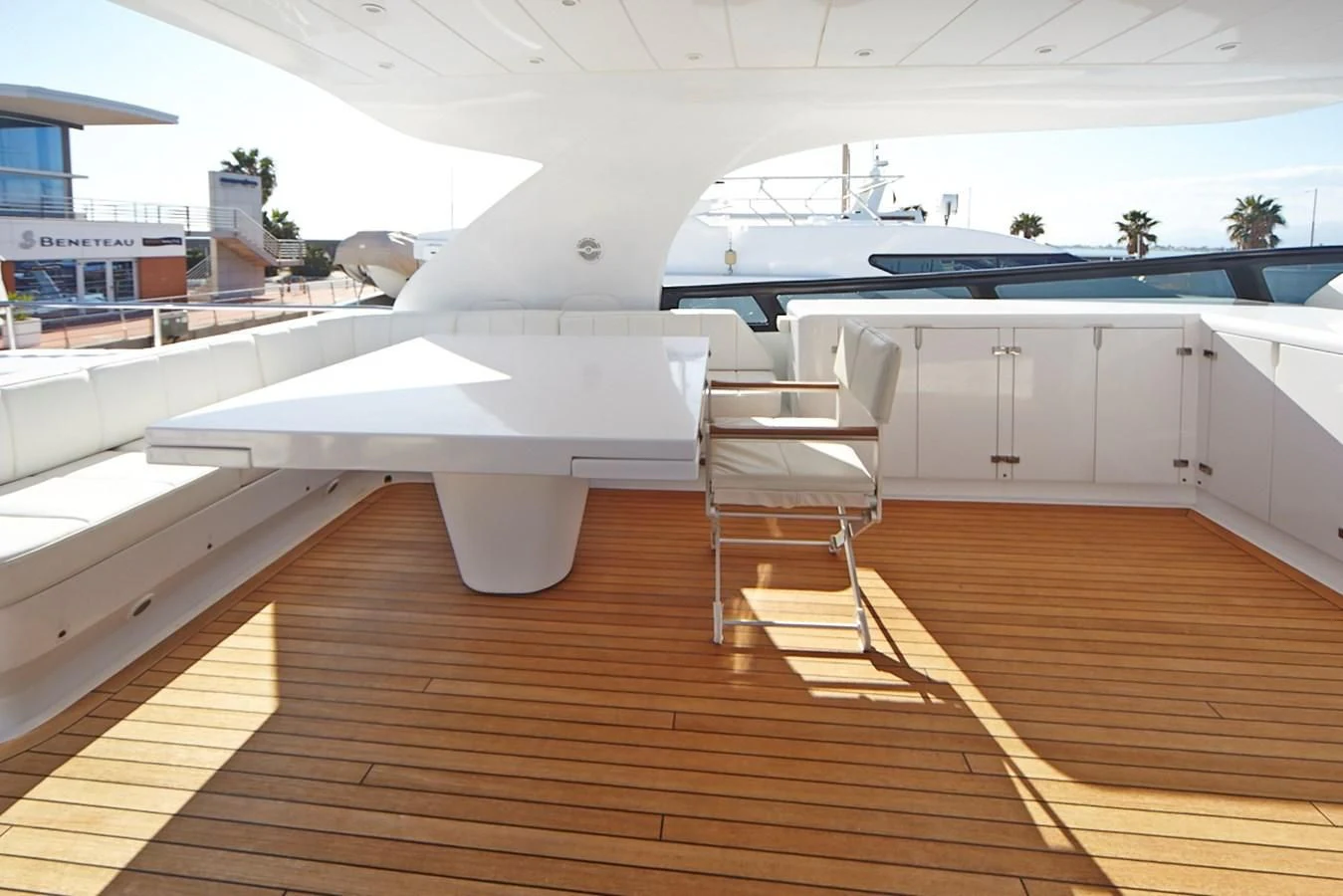 a wooden deck with a white chair and a white bench on it aboard GULU Yacht for Sale