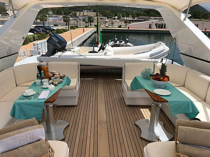 a deck with a table and chairs aboard PIERPAOLO IV Yacht for Sale