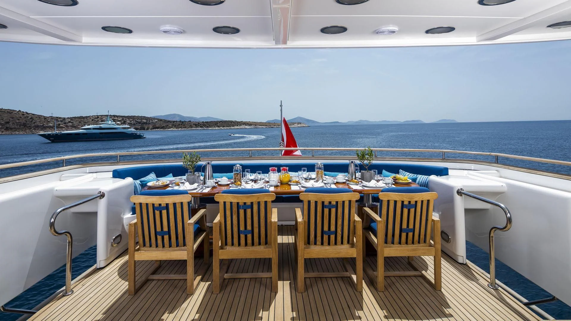 a table with chairs on a deck overlooking a body of water aboard JAAN Yacht for Sale
