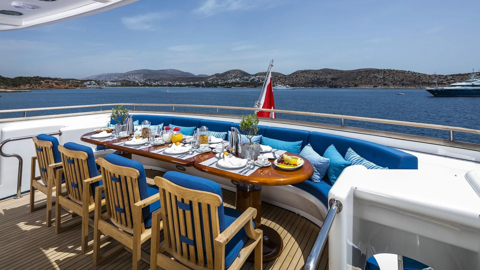 a table set for a meal on a deck overlooking a body of water aboard JAAN Yacht for Sale