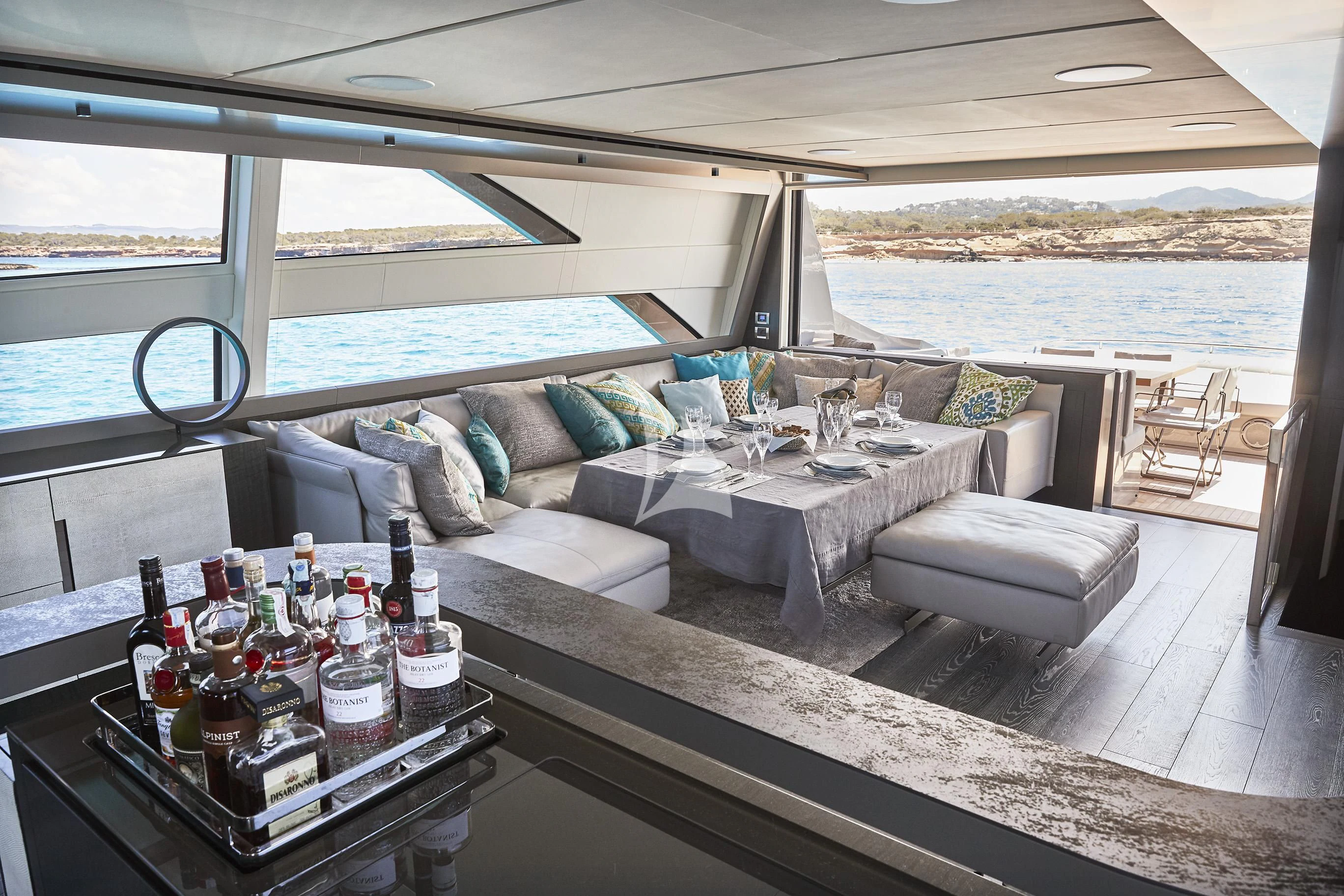 a living room with a couch and a table with bottles of wine aboard BALOO III Yacht for Sale