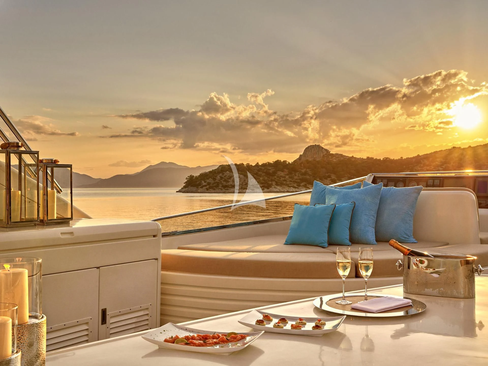 a large white patio with a large blue and white sofa and a view of a city and mountains aboard SANSARA Yacht for Sale