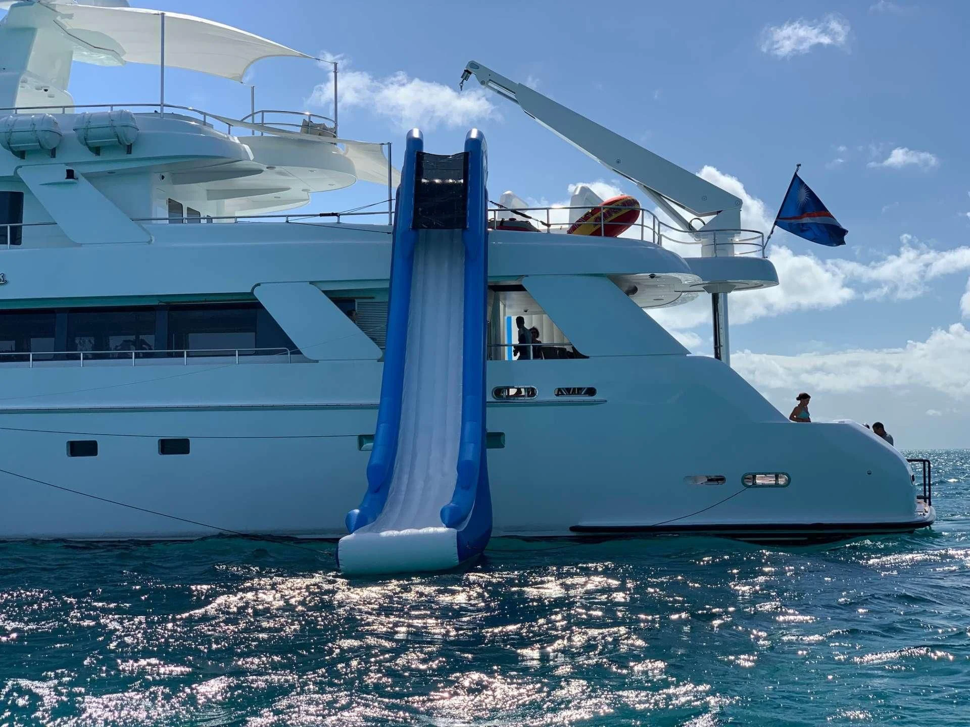 a large white boat with a blue flag on it aboard ISLAND HEIRESS Yacht for Charter