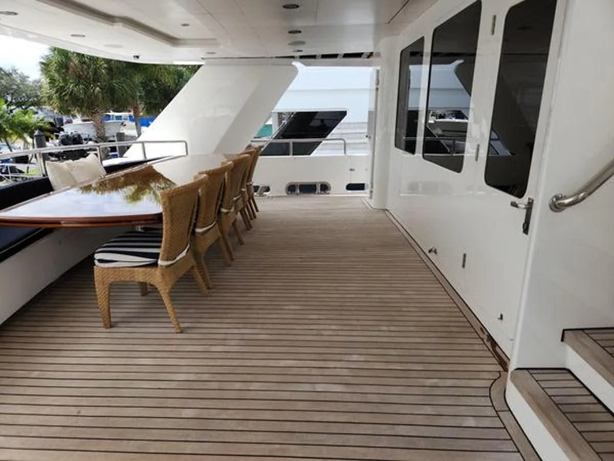 a wooden deck with chairs and a table and a white door aboard ISLAND HEIRESS Yacht for Charter