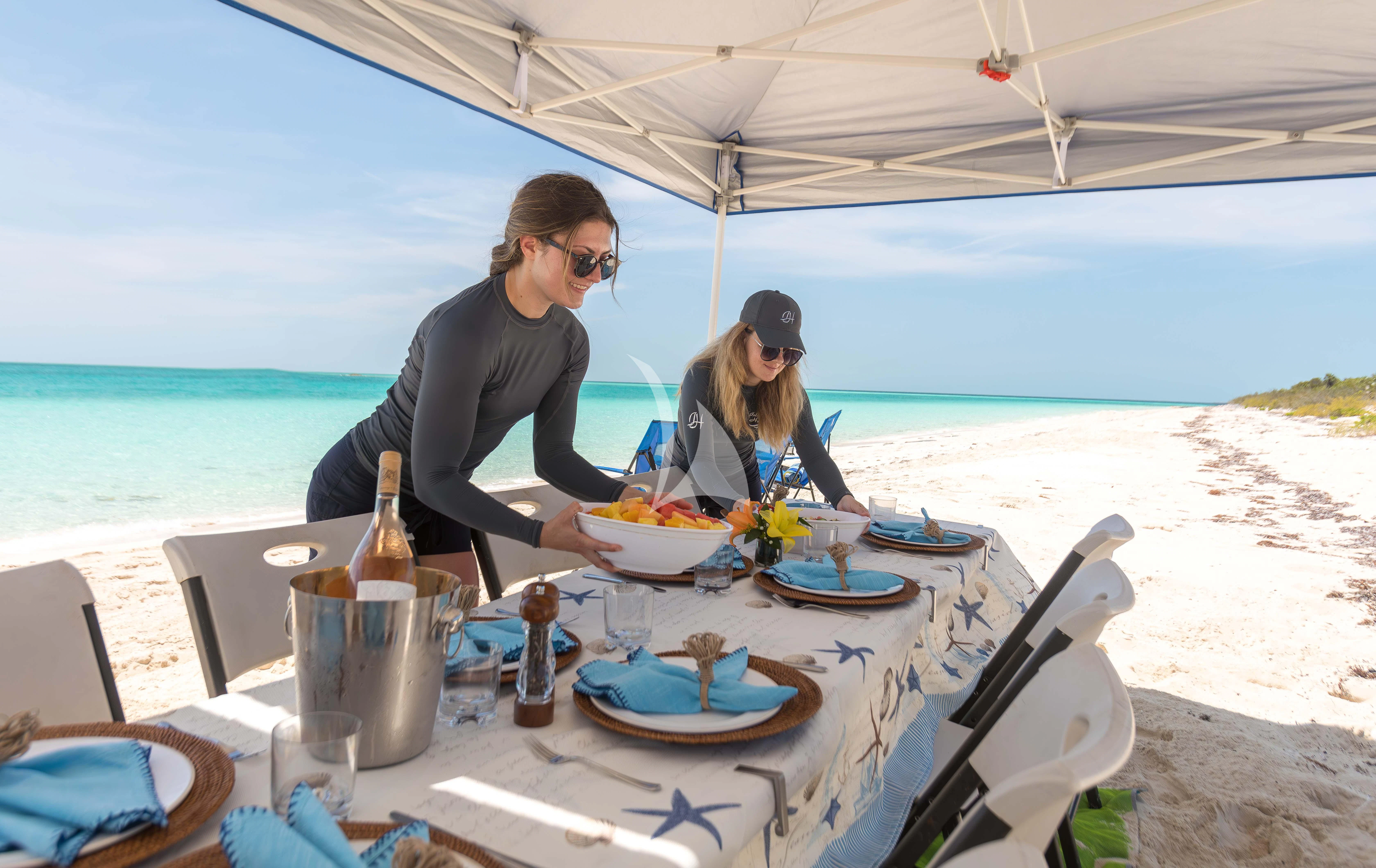 a man and a woman sitting at a table outside on a beach aboard ISLAND HEIRESS Yacht for Charter