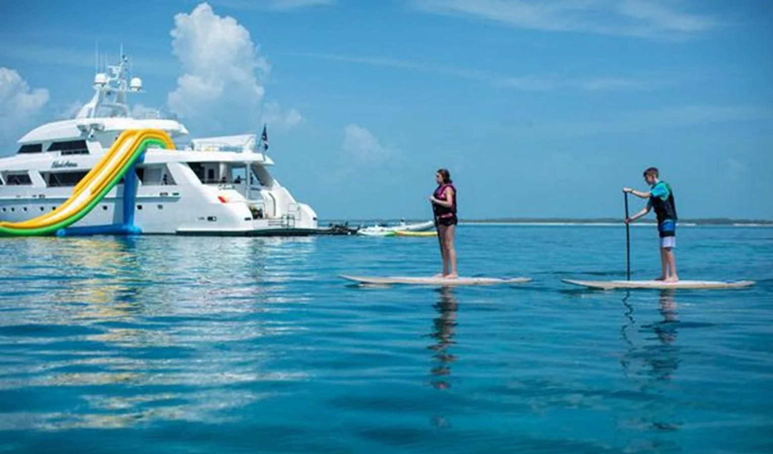 a couple of people stand on paddle boards in the water aboard ISLAND HEIRESS Yacht for Charter