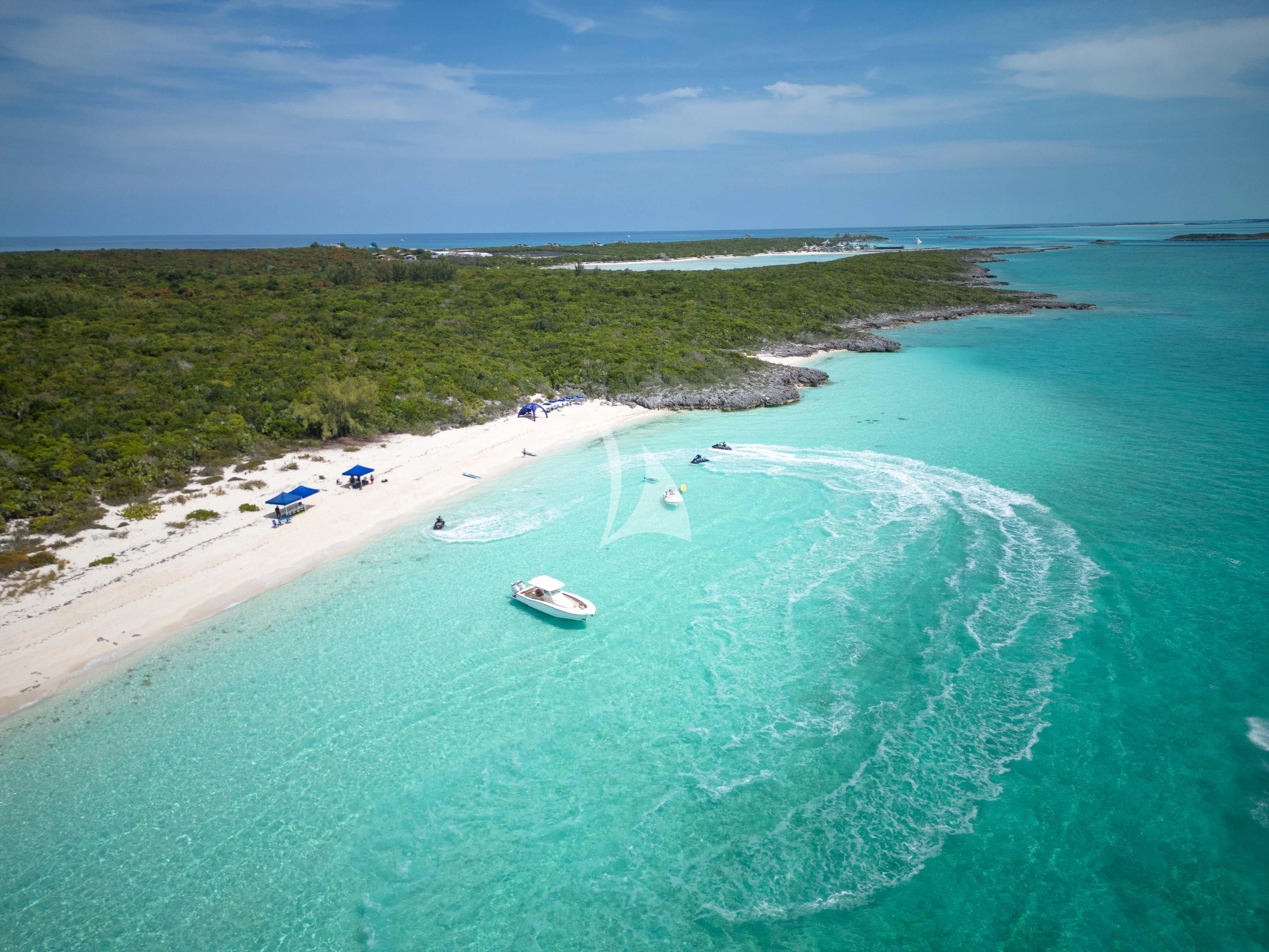 a beach with a boat and a beach and water aboard ISLAND HEIRESS Yacht for Charter