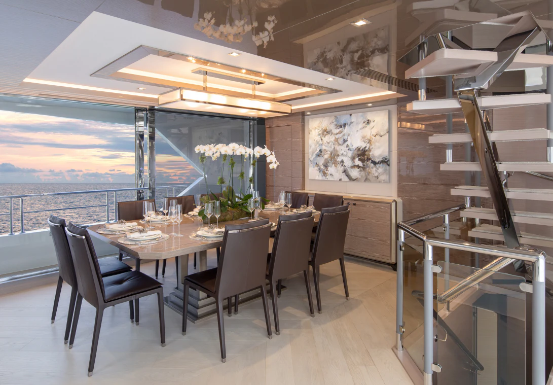 a dining table with chairs and a view of the ocean aboard MÖBIUS Yacht for Sale