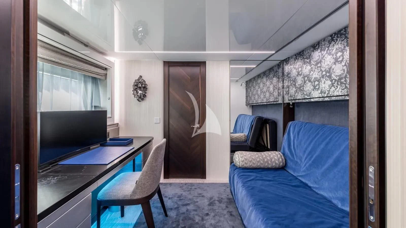 a bedroom with a blue couch and a television aboard EXIT Yacht for Sale