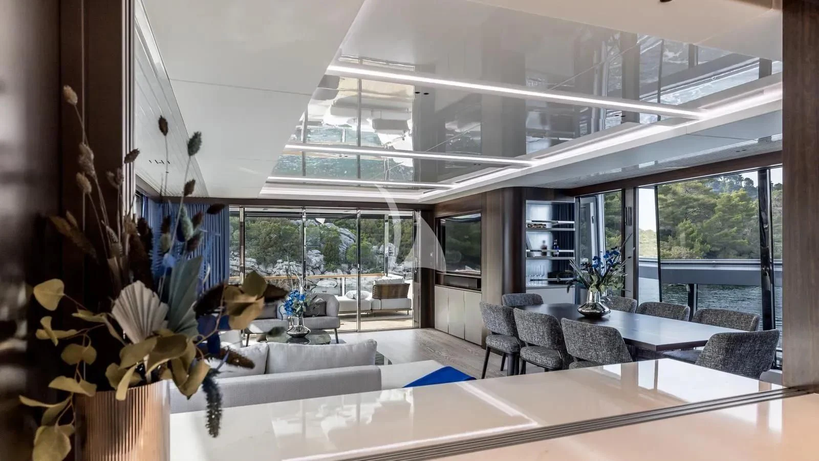 a room with a large window and a table with chairs and plants aboard EXIT Yacht for Sale