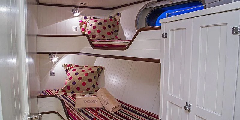 a bed with pillows and a book aboard PAOLYRE Yacht for Sale