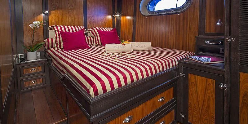 a bed with red and white sheets aboard PAOLYRE Yacht for Sale