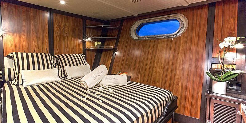 a bed with a black and white checkered sheet and a mirror on the wall aboard PAOLYRE Yacht for Sale