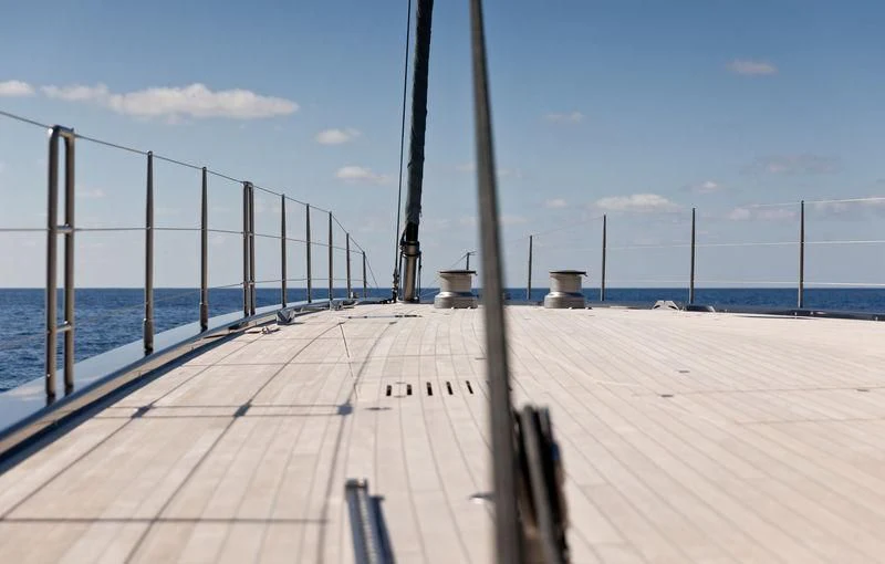 a boardwalk with a railing and a body of water in the background aboard NGONI Yacht for Sale