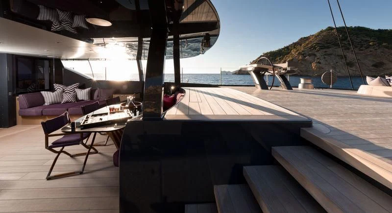 a deck with a pool and a beach and a building in the background aboard NGONI Yacht for Sale