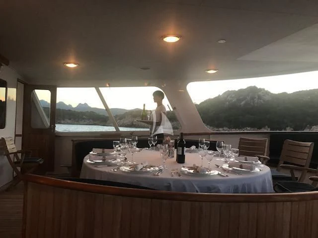 a person standing next to a table with wine glasses aboard SECRET LIFE Yacht for Sale