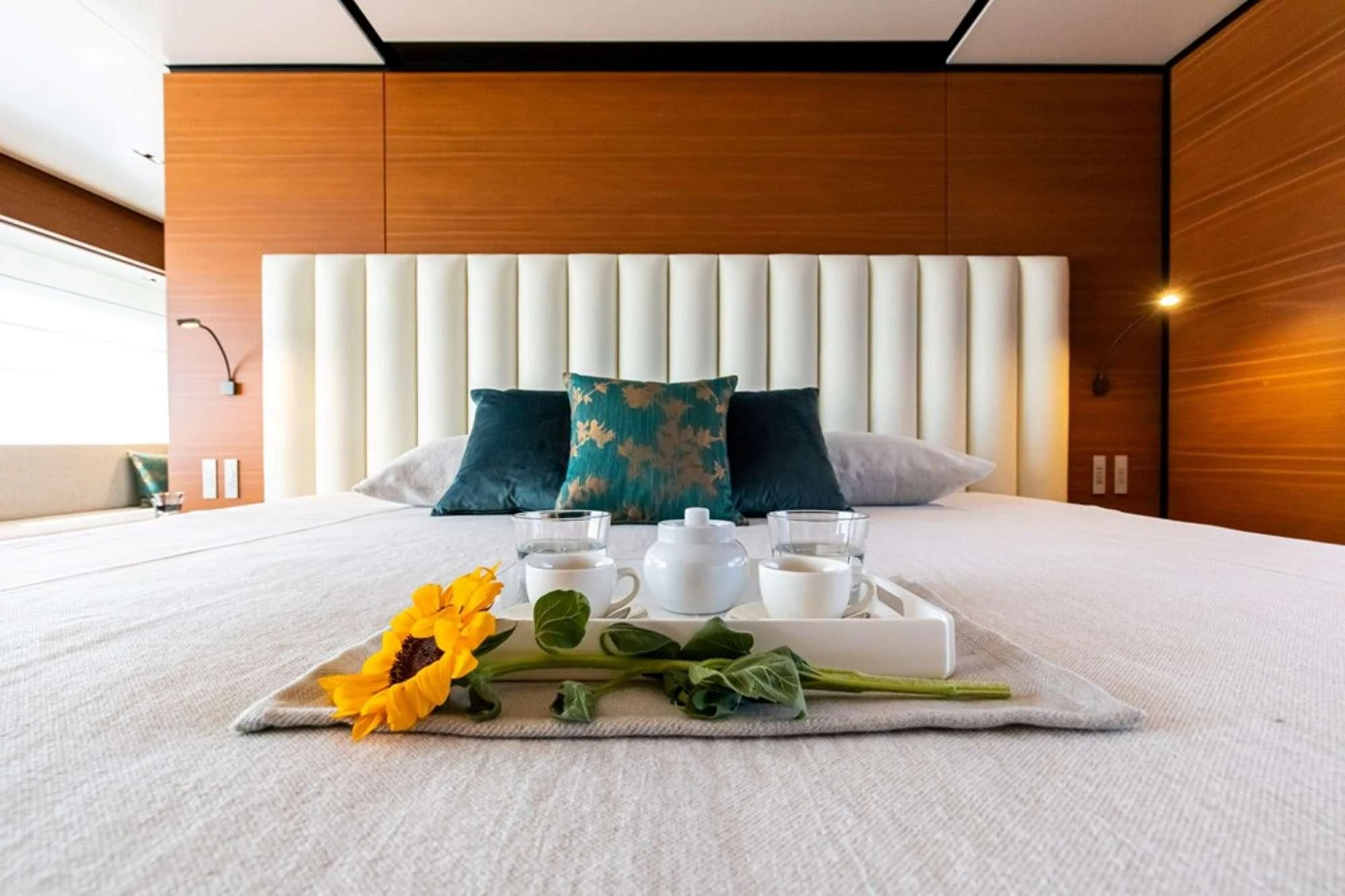 a bed with a white sheet and a vase with yellow flowers on it aboard SOUTH Yacht for Sale