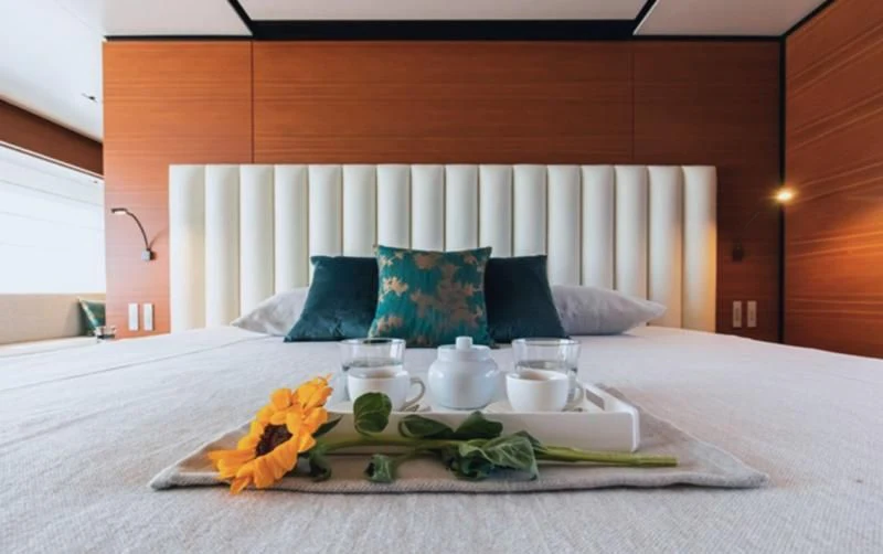 a bed with a tray of food and a tray with a tea set aboard SOUTH Yacht for Sale