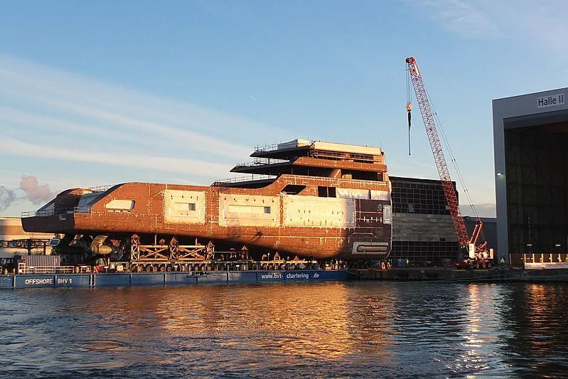 a large container ship docked at a port aboard SOLARIS Yacht for Sale