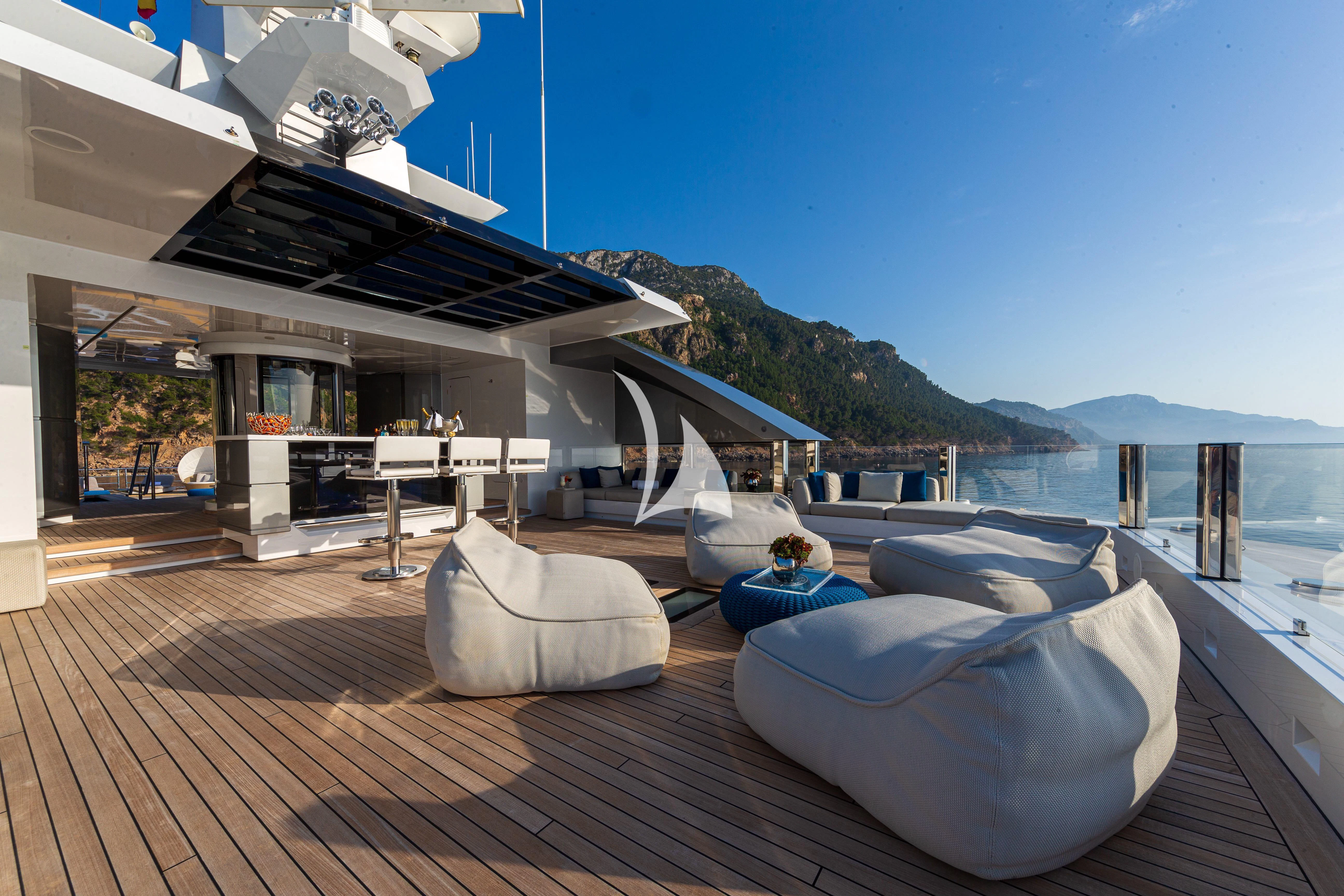 a deck with a large pool and a deck with a view of the mountains and water aboard STELLA MARIS Yacht for Sale