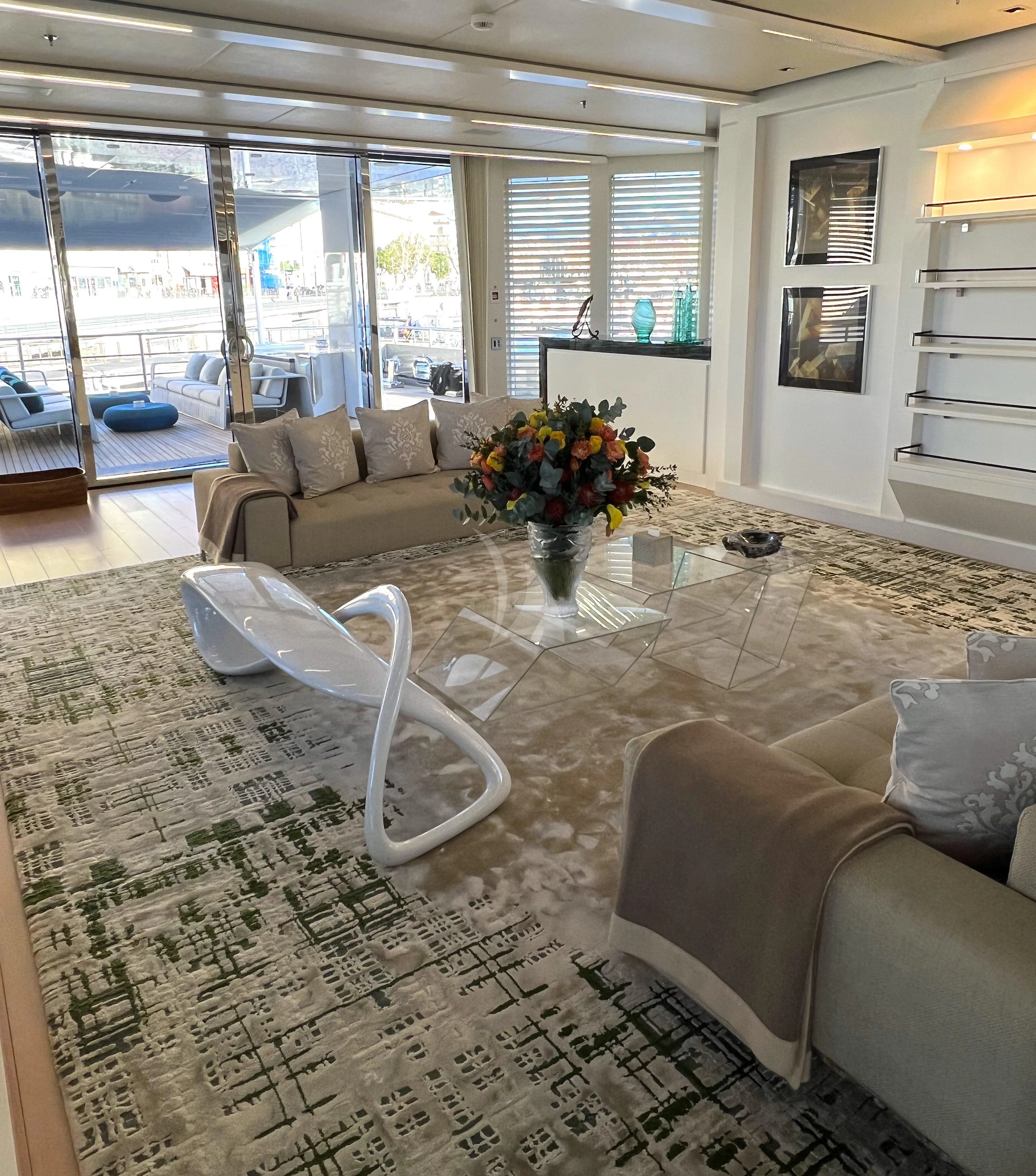 a living room with a glass table and a white chair aboard STELLA MARIS Yacht for Sale