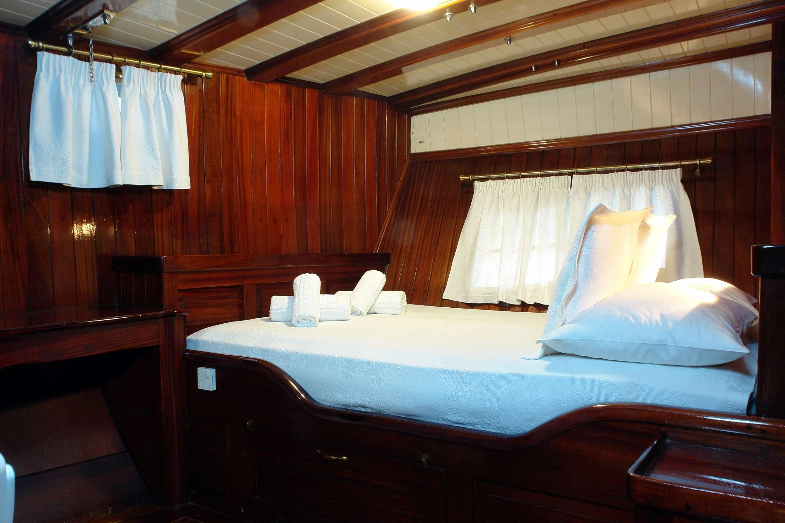 a bed with white sheets aboard ERATO Yacht for Charter