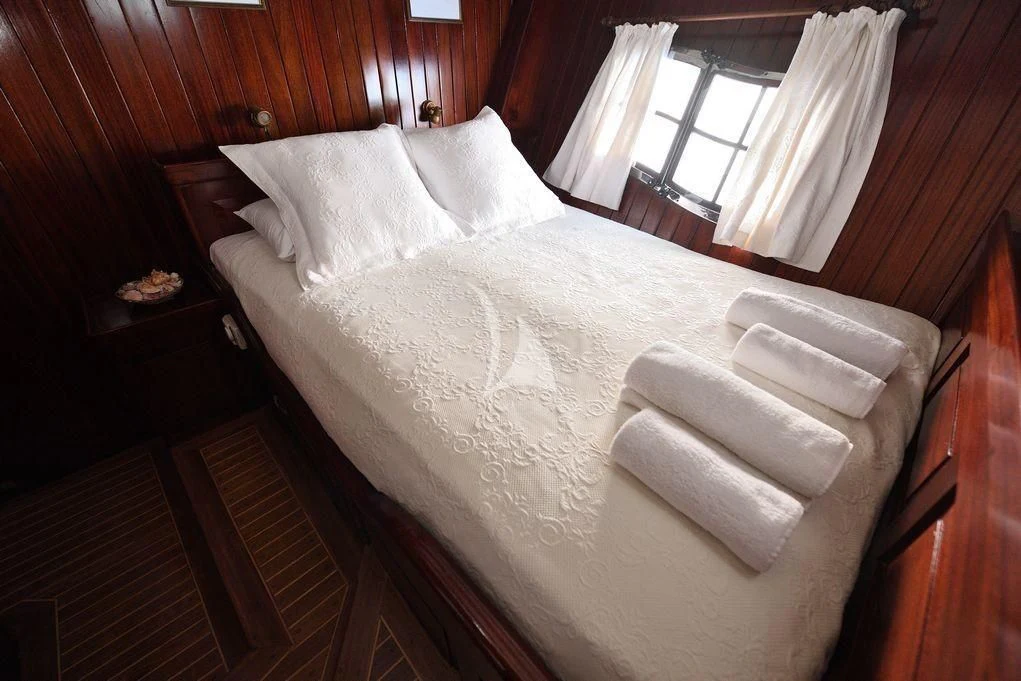 a bed with white sheets aboard ERATO Yacht for Charter