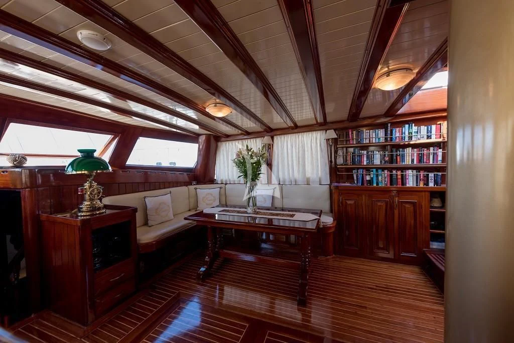 a living room with a bookcase and a table aboard ERATO Yacht for Charter