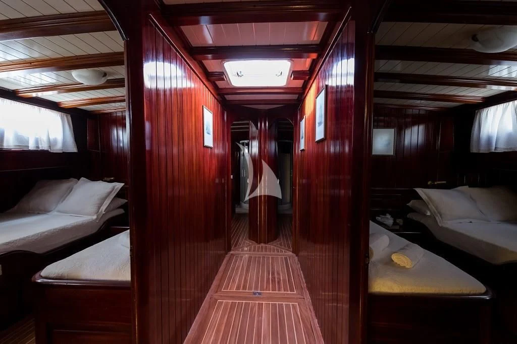 a room with beds and a red wall aboard ERATO Yacht for Charter