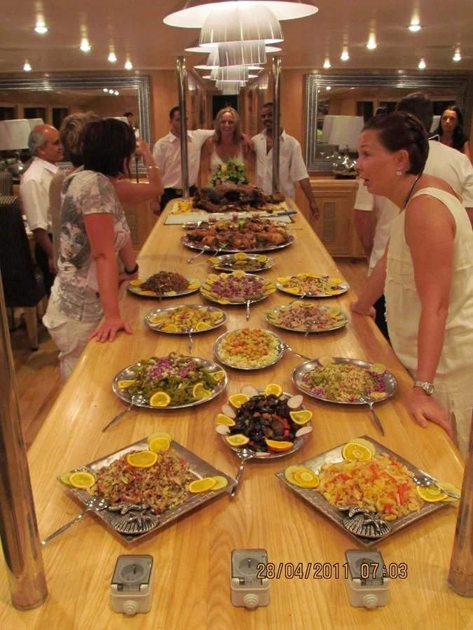 a group of people standing around a table full of food aboard SCUBA SCENE Yacht for Sale