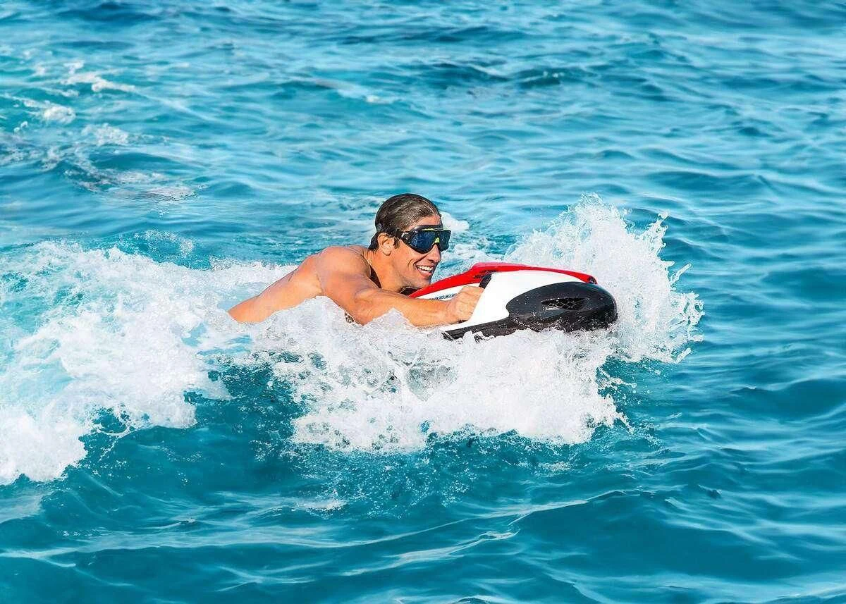 a man riding a surfboard aboard SERENISSIMA III Yacht for Charter