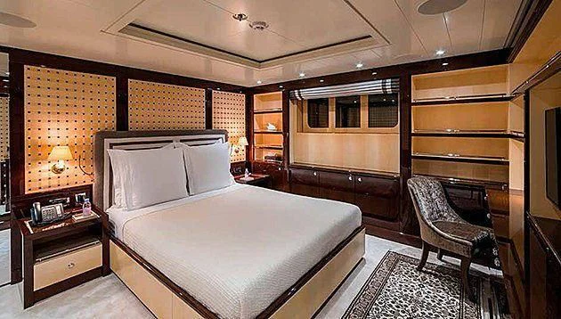 a bedroom with a bed and a desk aboard LA FAMILIA Yacht for Sale