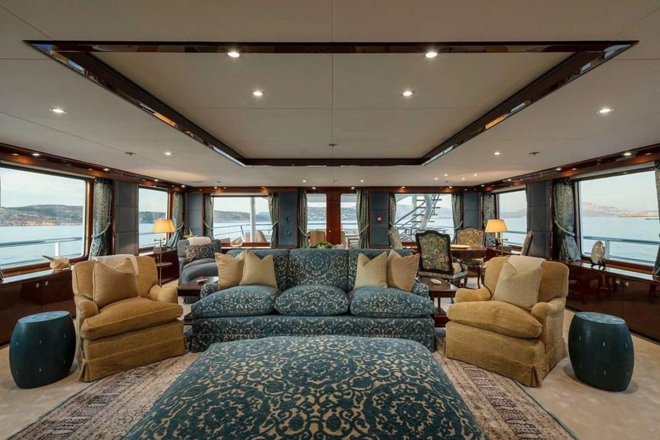 a living room with a large blue couch and a large window aboard LA FAMILIA Yacht for Sale