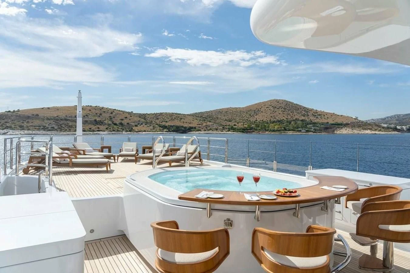 a table and chairs on a deck overlooking a body of water aboard LA FAMILIA Yacht for Sale
