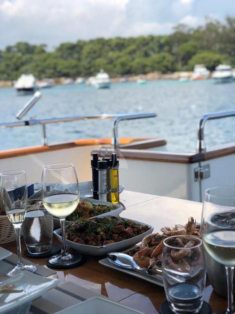 a table with food and glasses on it by a body of water aboard SOLAL Yacht for Sale