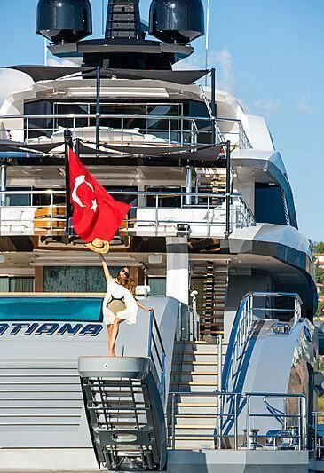 a person standing on a ship holding a flag aboard TATIANA Yacht for Sale