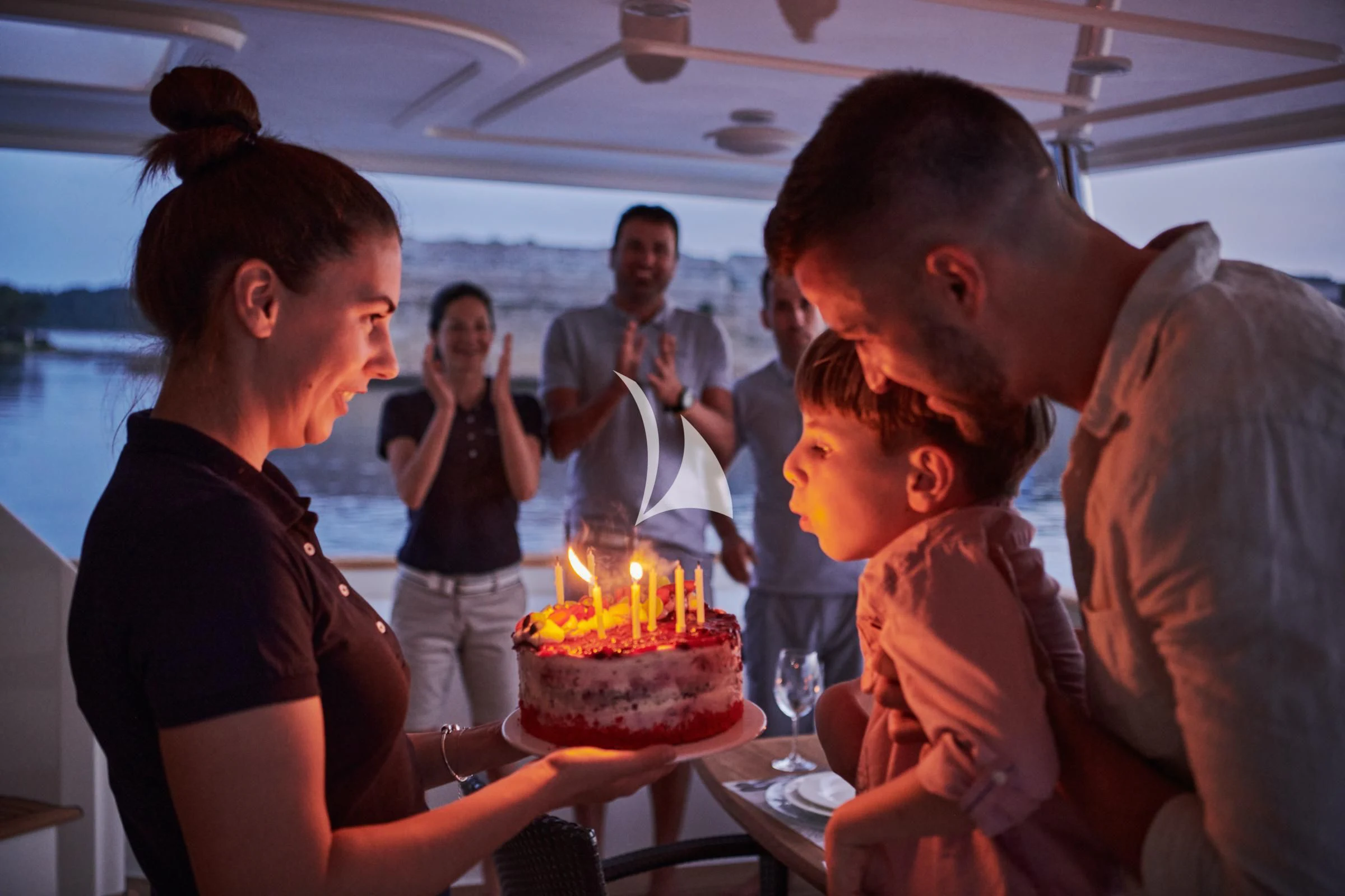 a group of people around a cake aboard FRIEND'S BOAT Yacht for Charter