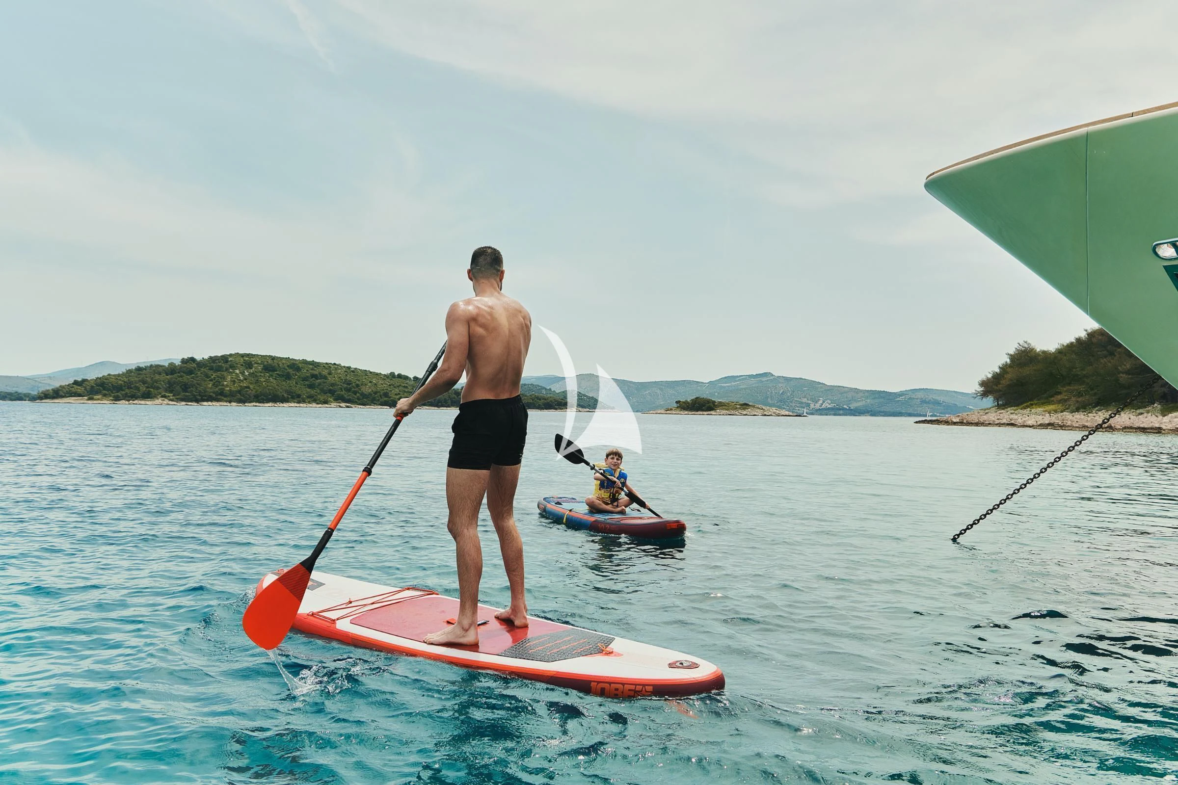 a man and a boy on a paddle board in the water aboard FRIEND'S BOAT Yacht for Charter