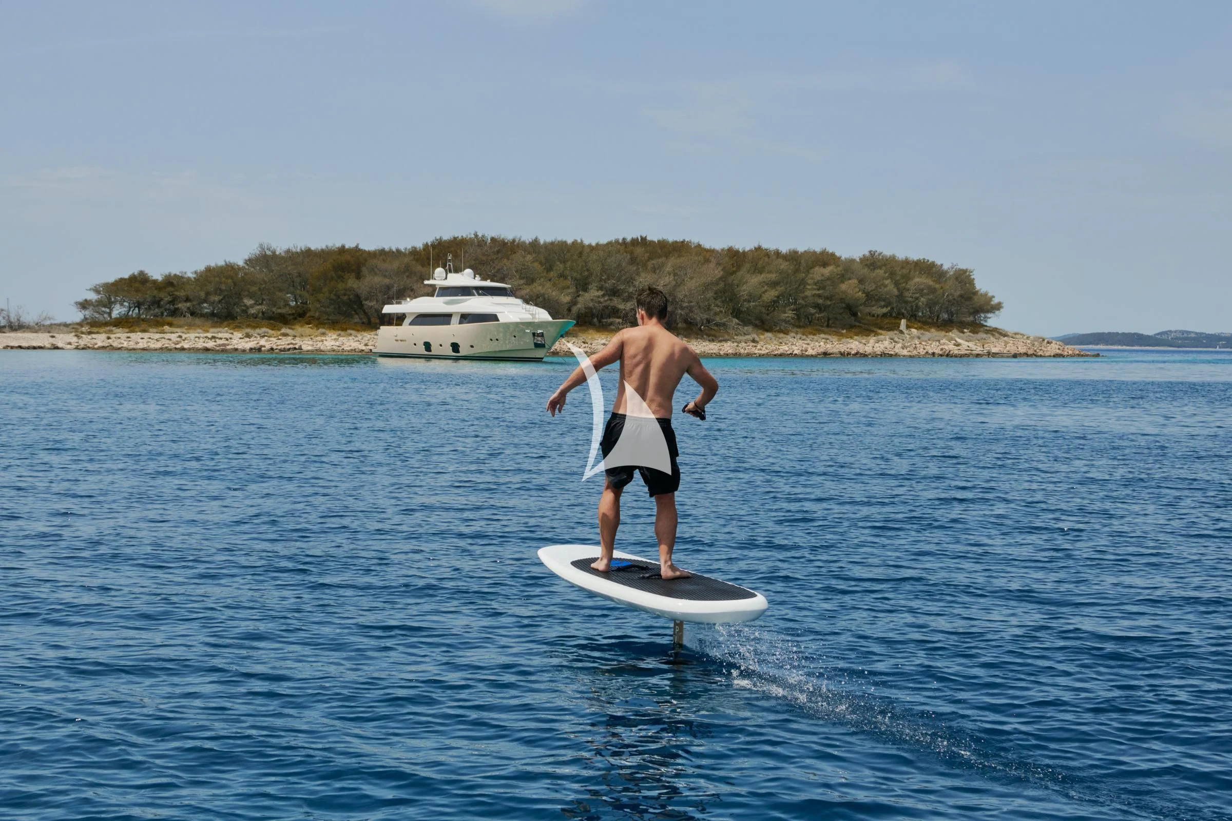 a man on a surfboard in the water with a boat in the background aboard FRIEND'S BOAT Yacht for Charter