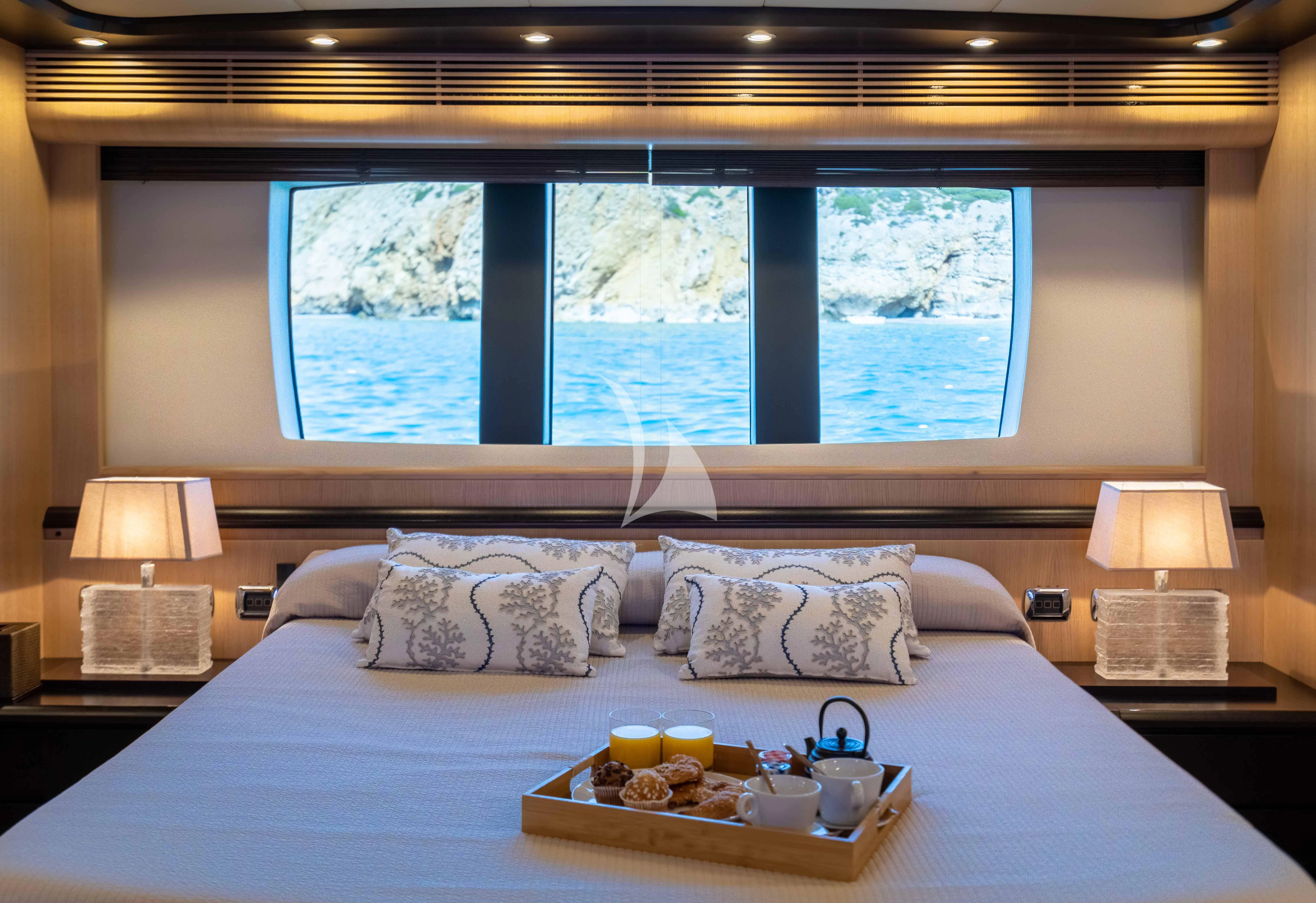 a bed with a tray of food and a window aboard DOLCE VITA IV Yacht for Sale
