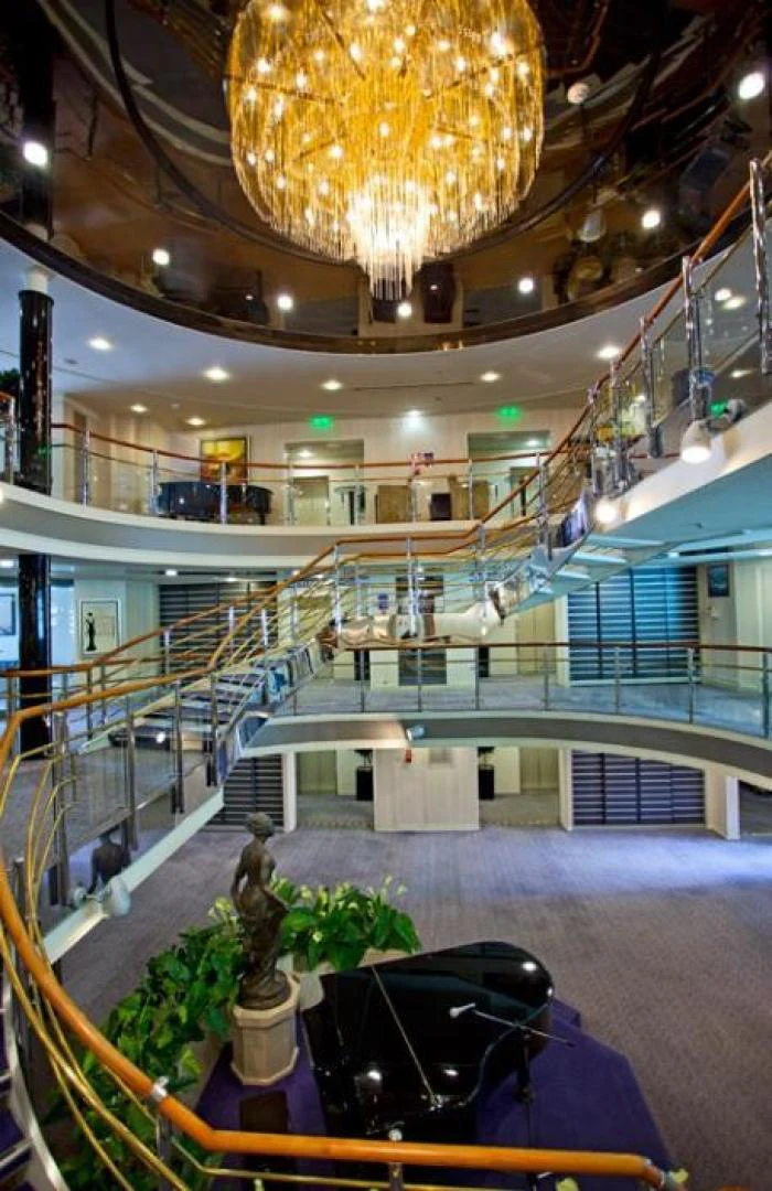 a large indoor mall with a fountain and a statue in the center aboard AEGEAN PARADISE Yacht for Sale